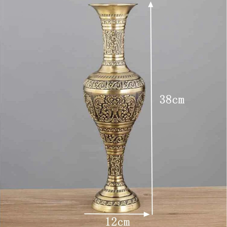 Decorative gold vase with intricate patterns on a wooden surface and gray background